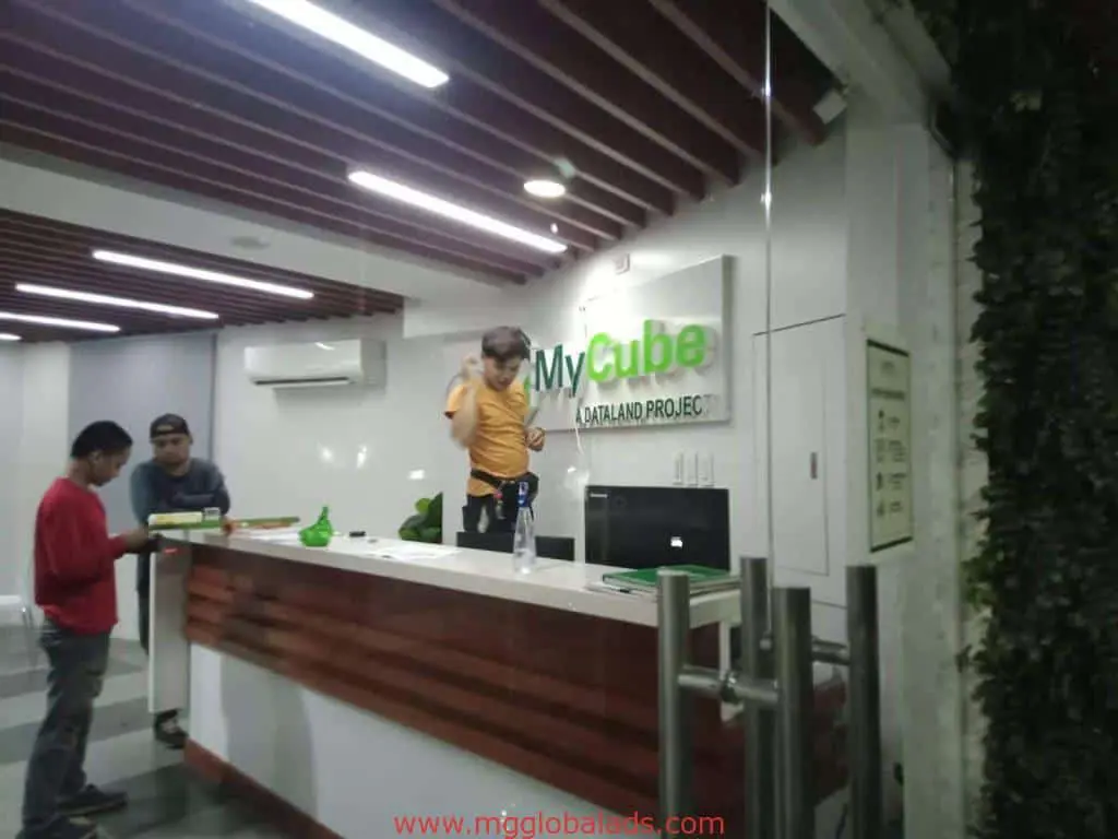 Acrylic building signage for MyCube OLANAD PROJECT at a modern office lobby in Makati, with people at the reception by M&G Global Ads.
