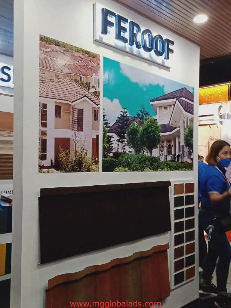 Metallic FEROOF booth signage with roofing samples at an Ortigas event, person in blue shirt visible. by M&G Global Ads.
