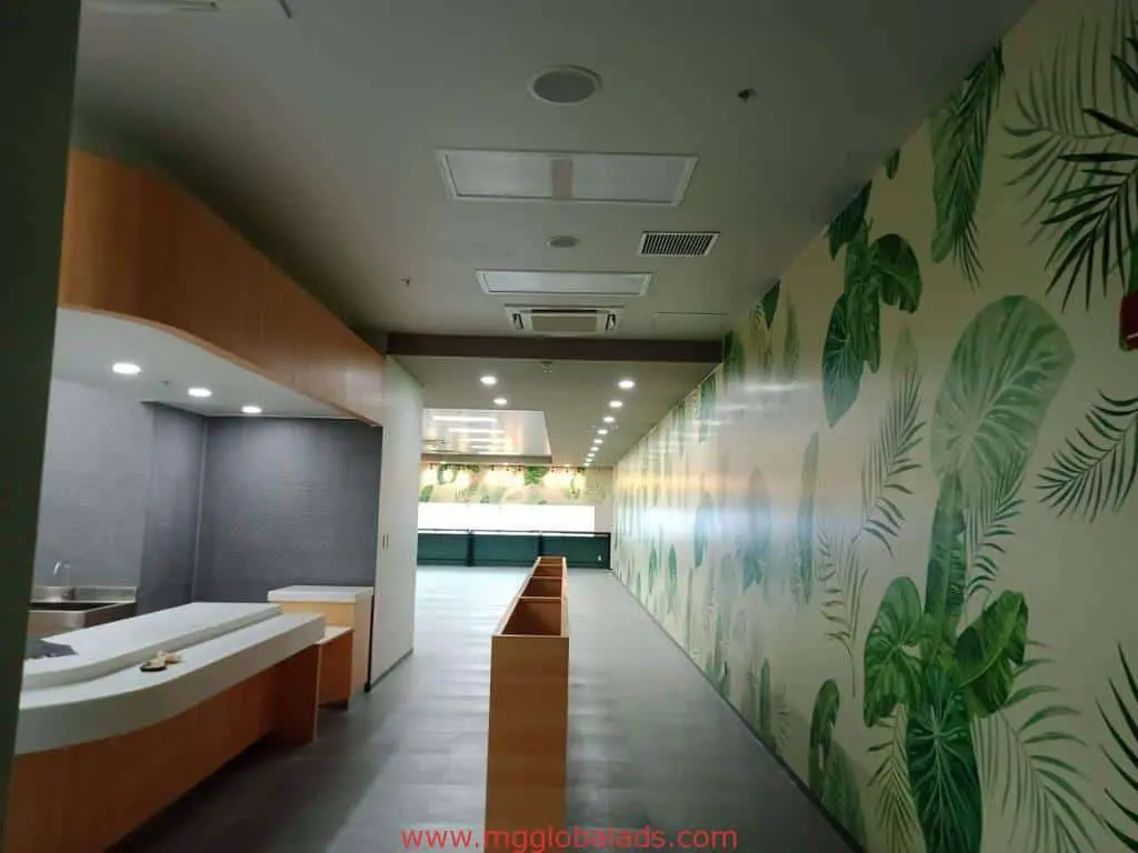 Sleek indoor wayfinding signage in a modern hallway, wood counters, tropical leaf wall, minimalist Ortigas interior by M&G Global Ads.