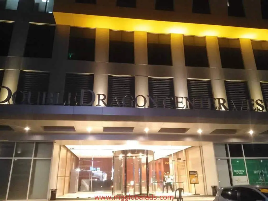 Acrylic signage DOUBLEDRAGON CENTRE at modern building entrance in Ortigas, Opening Soon sign visible, by M&G Global Ads.