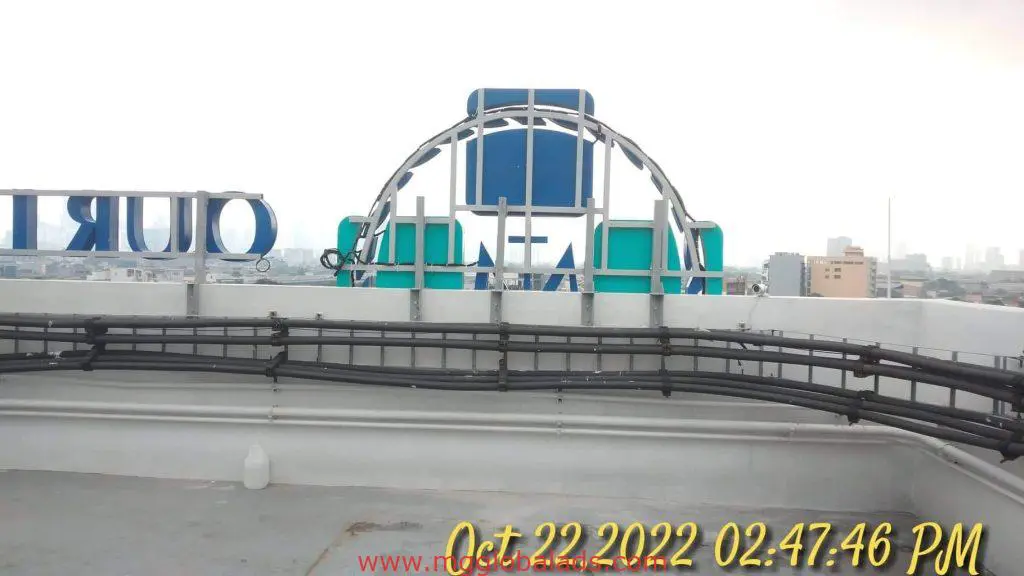 Acrylic billboard signage on rooftop in Makati, black cables and city skyline in background, by M&G Global Ads.