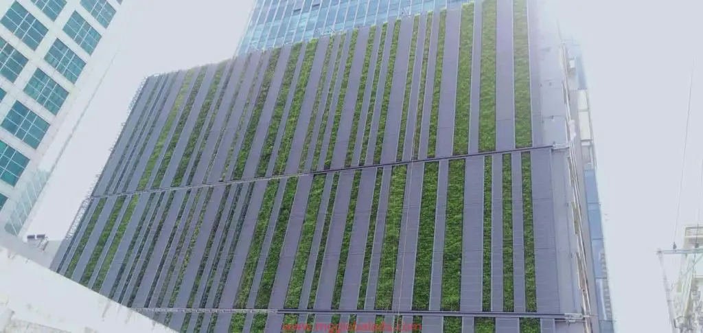 Tall building with vertical garden, dark panels, LED signage in Makati urban skyline by M&G Global Ads.