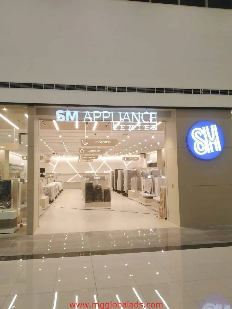 SM Appliance Center acrylic signage with illuminated logo at store entrance in Quezon City, bright modern design by M&G Global Ads.