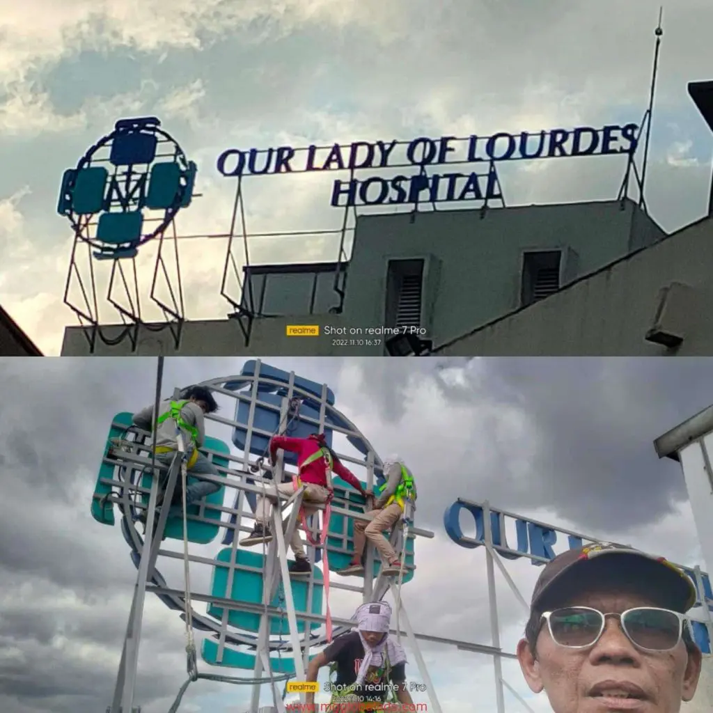 Hospital rooftop LED signage for Our Lady of Lourdes Hospital in Quezon City; workers repair the sign—by M&G Global Ads.