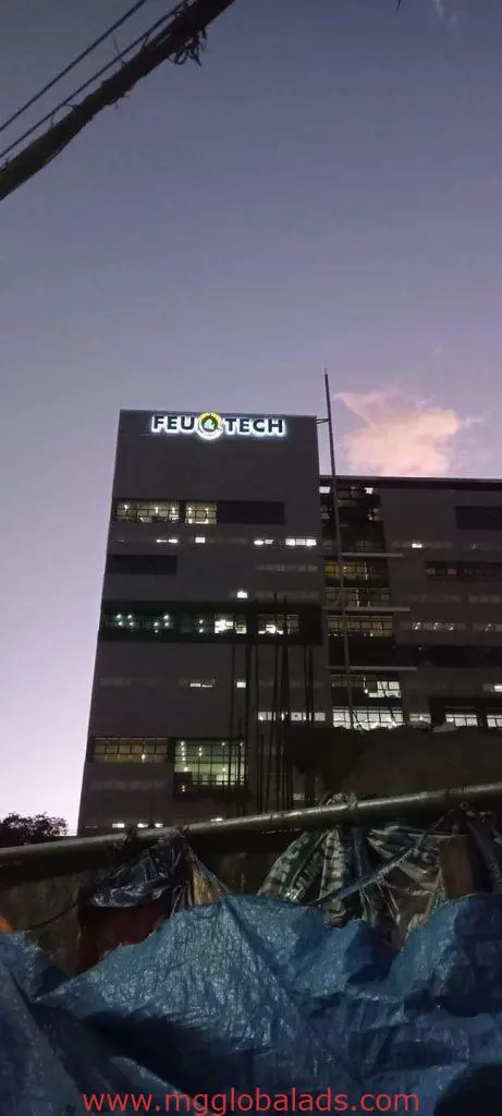 FEU TECH outdoor building signage in Quezon City illuminated at dusk, construction materials in foreground by M&G Global Ads.