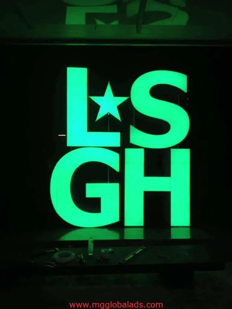 LSGH custom LED signage with star accent, lit at night in San Juan by M&G Global Ads. Some tools visible at the base.