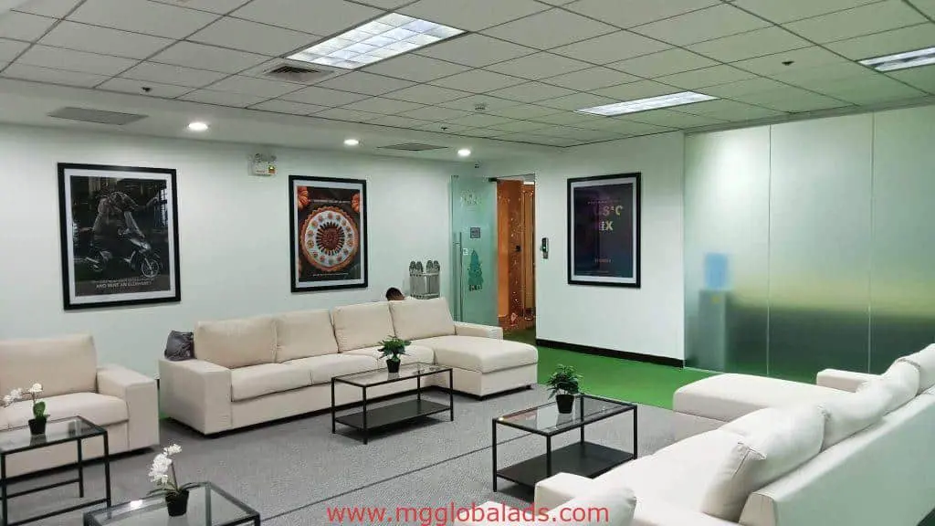 Modern office lounge with indoor acrylic signage in Makati, white sofas, glass tables, and plants. By M&G Global Ads.