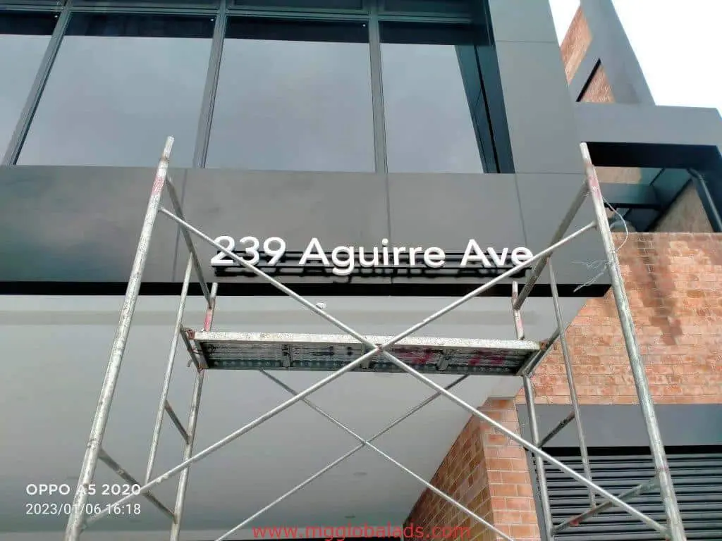 Metal building address signage for 239 Aguirre Ave in Makati with scaffold setup, entrance view by M&G Global Ads.