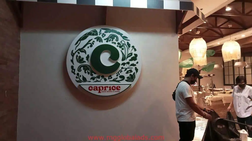 Round restaurant indoor signage for Caprice in Makati, with green C logo, hanging lights, leafy decor by M&G Global Ads.