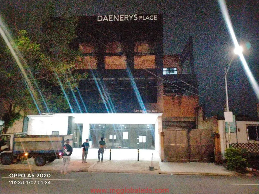 Acrylic signage for Daenerys Place above a brightly lit entrance in Makati at night, people nearby. By M&G Global Ads.