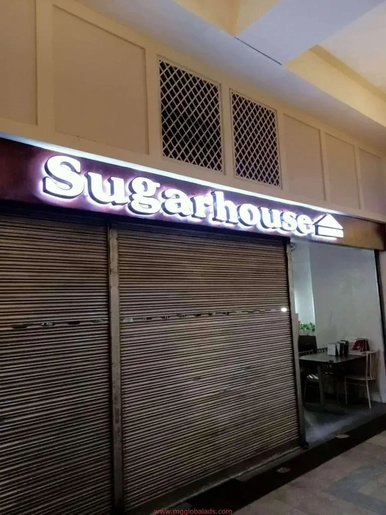 Sugarhouse stainless storefront sign with metal shutters down in Makati, glimpse of tables inside by M&G Global Ads.