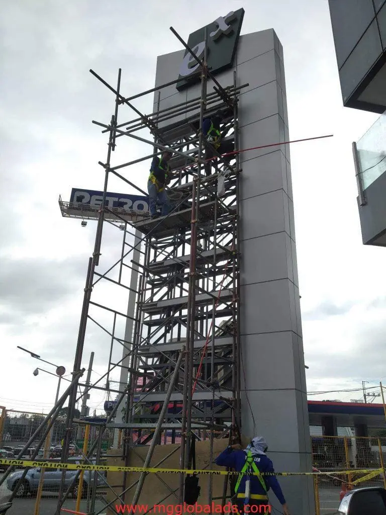 LED signage installation by three workers on scaffolding in Quezon City under overcast sky, by M&G Global Ads.
