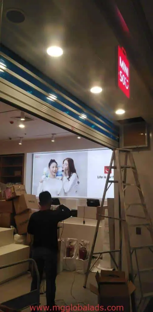 MINISO new building signage installation in Mandaluyong, with screen display, under construction store by M&G Global Ads.