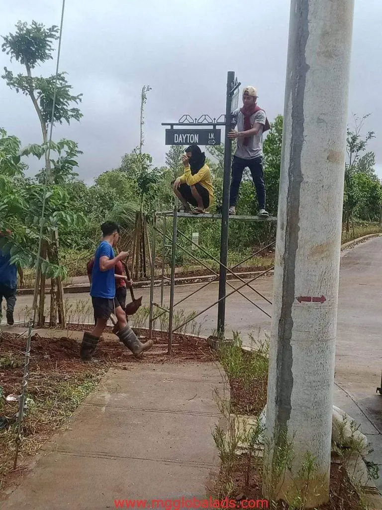 Outdoor directional signage installation for DAYTON LN in Quezon City; workers on scaffolding. by M&G Global Ads.