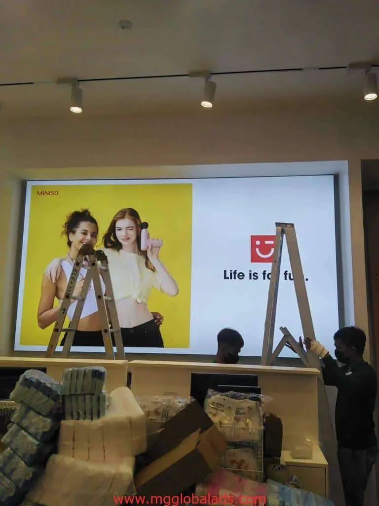 MINISO building poster signage installation in front of store in Makati, with ladder setup by M&G Global Ads.