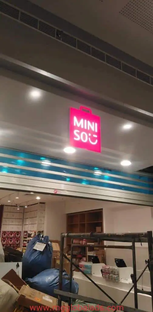 MINISO illuminated LED storefront signage in Makati, above a partially set-up retail store, by M&G Global Ads.