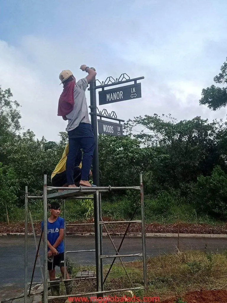 A man and a boy stand on a metal structure near billboard signage in BGC by M&G Global Ads.