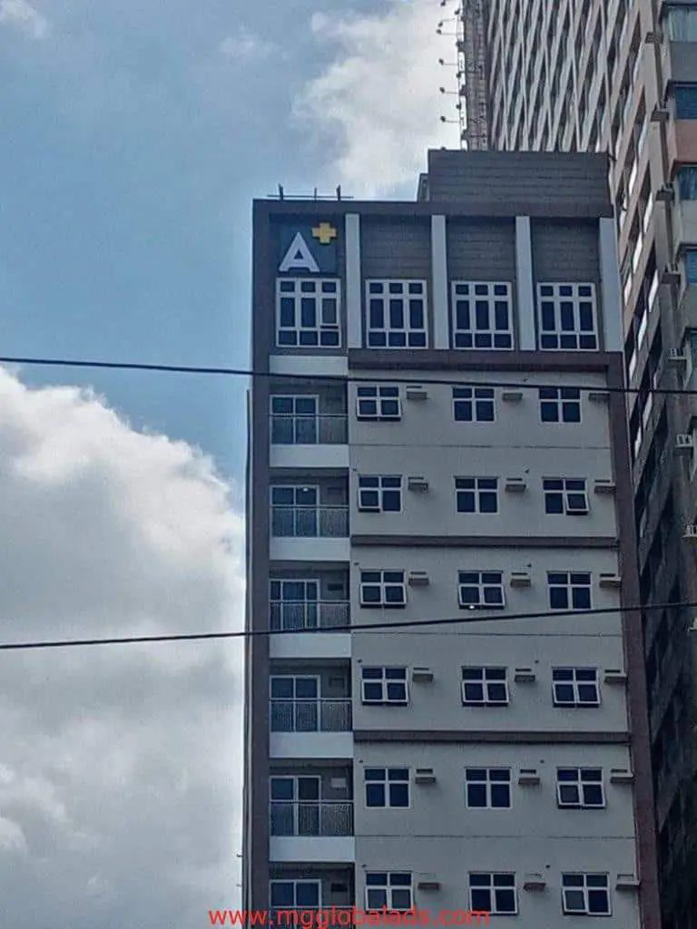 Rooftop building signage, large A+ logo, on a tall building in Makati, prominent against partly cloudy sky by M&G Global Ads.