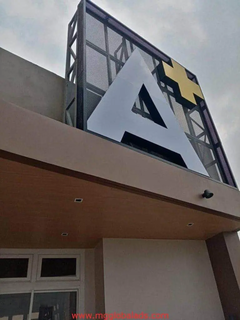 Building facade channel letter signage with bold A and yellow plus in Makati, photographed from low angle by M&G Global Ads.
