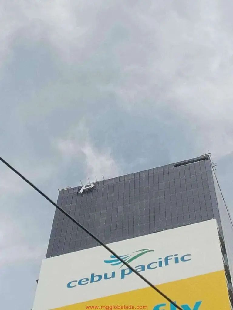 Cebu Pacific LED signage and metallic letter P sign installation on a tall building in Makati, cloudy sky—by M&G Global Ads.