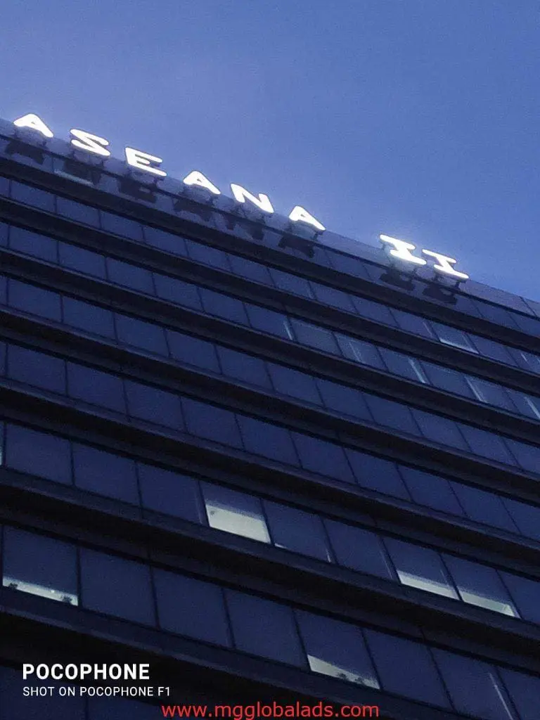 Illuminated LED building signage for ASEANA II on a tall glass tower, evening in Makati cityscape by M&G Global Ads.