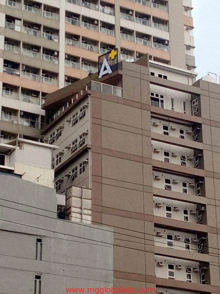 Rooftop LED signage for client A with yellow plus sign on tall building in Ortigas, Metro Manila by M&G Global Ads.