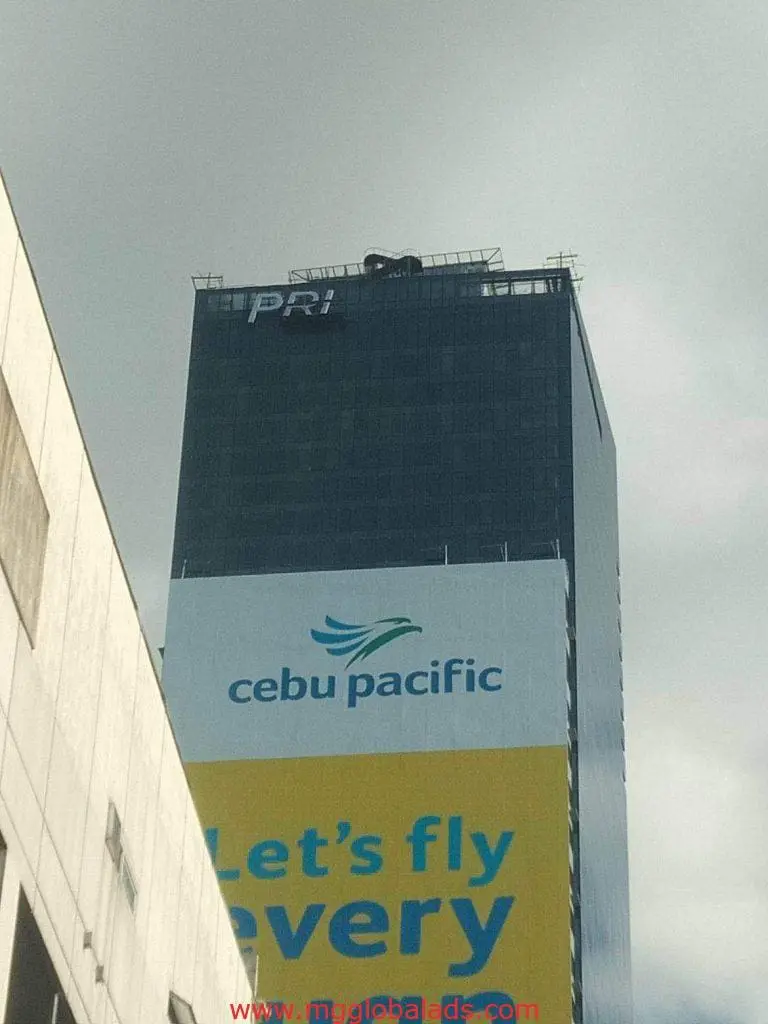 Building signage with PRI sign and Cebu Pacific billboard in Ortigas, cloudy sky background, by M&G Global Ads.