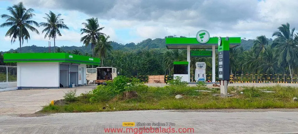 Green and white gas station with LED signage and two fuel pumps in Quezon City, truck nearby, by M&G Global Ads.