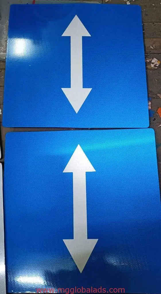 Two-way traffic building signage in Makati: two blue square signs with white arrows up and down, stacked. By M&G Global Ads.