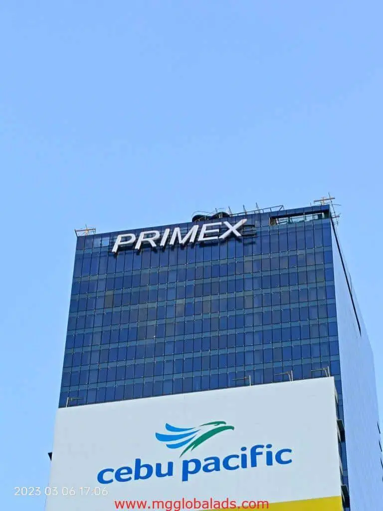 Metallic PRIMEX building signage and Cebu Pacific billboard in Makati under clear sky by M&G Global Ads.