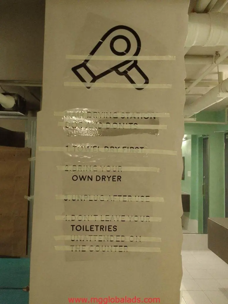 Laundry rules acrylic building signage on beige wall in Mandaluyong, partially covered by tape, by M&G Global Ads.