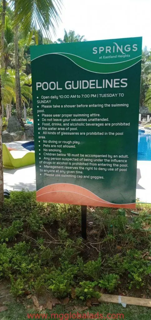 Outdoor pool signage for SPRINGS at Eastland Heights, Quezon City, showing pool rules and lush trees by M&G Global Ads.