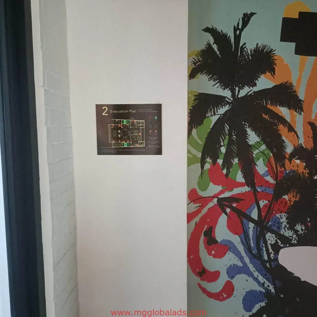Metallic evacuation plan signage with map on palm tree mural wall in Mandaluyong office by M&G Global Ads.
