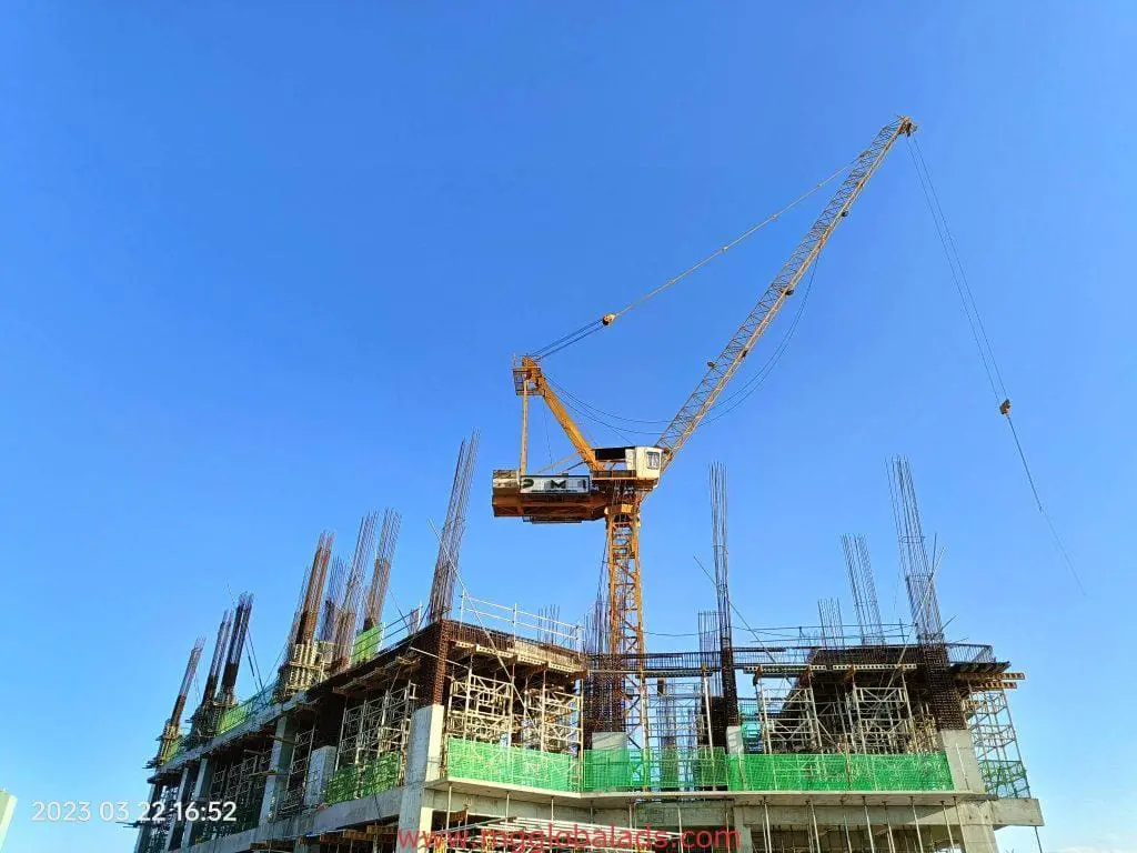Construction site metallic signage in Makati with crane, scaffolding, and steel rods under blue sky by M&G Global Ads.