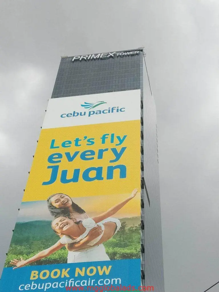 Cebu Pacific LED building signage in Quezon City displays “Let’s fly every Juan” with 2 smiling people. by M&G Global Ads.