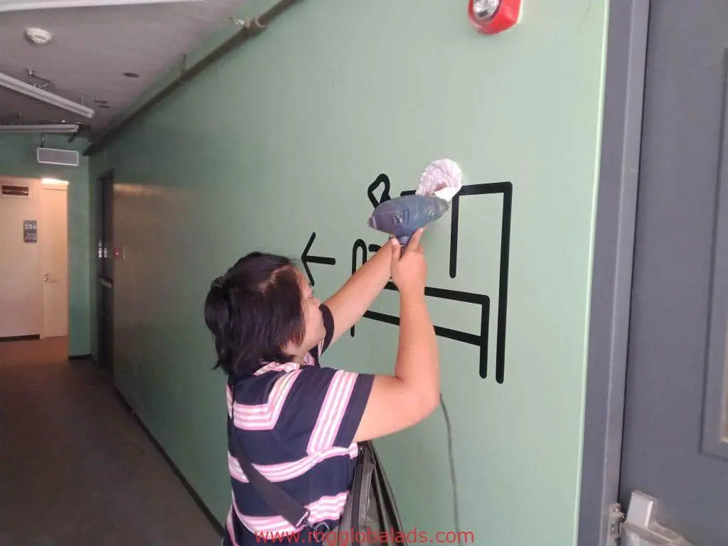 Building hallway wall mural signage in Mandaluyong; person interacts with playful sleeping bed art, by M&G Global Ads.