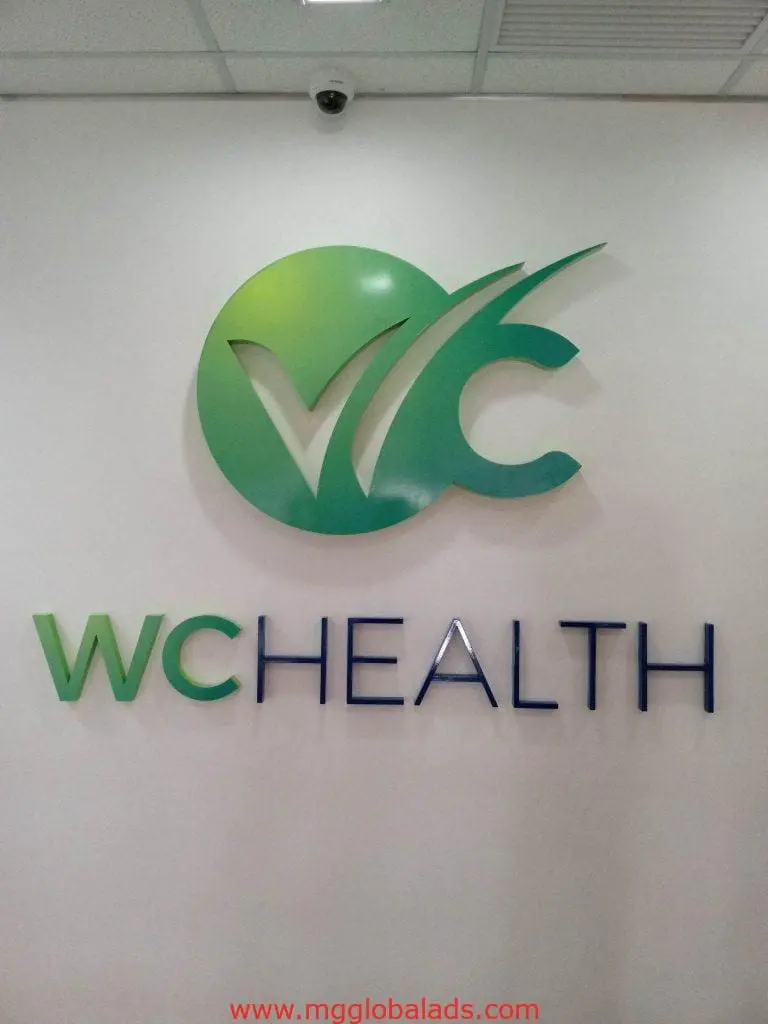 Indoor acrylic signage for WCHEALTH with green-blue logo, installed in Quezon City office by M&G Global Ads.