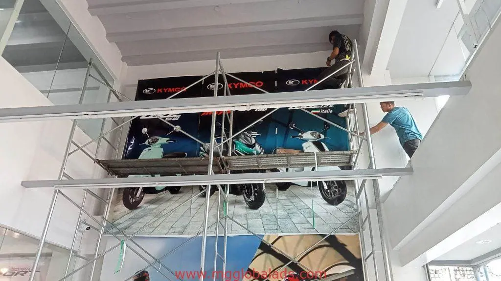 KYMCO indoor signage installation in a bright Quezon City showroom, with scooter ad display, by M&G Global Ads.