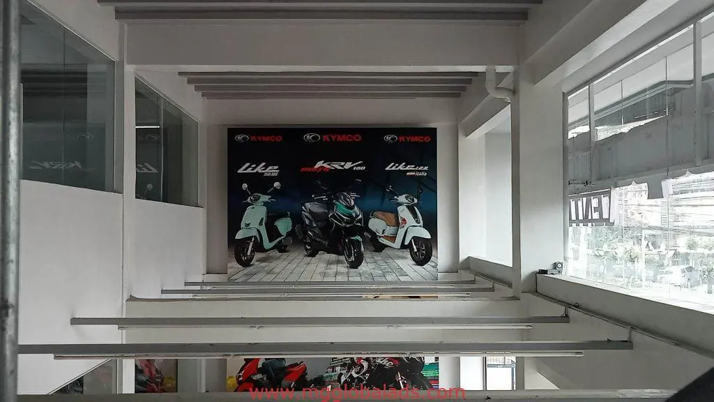 KYMCO scooter backdrop signage with logo and model names at a modern showroom in Makati by M&G Global Ads.