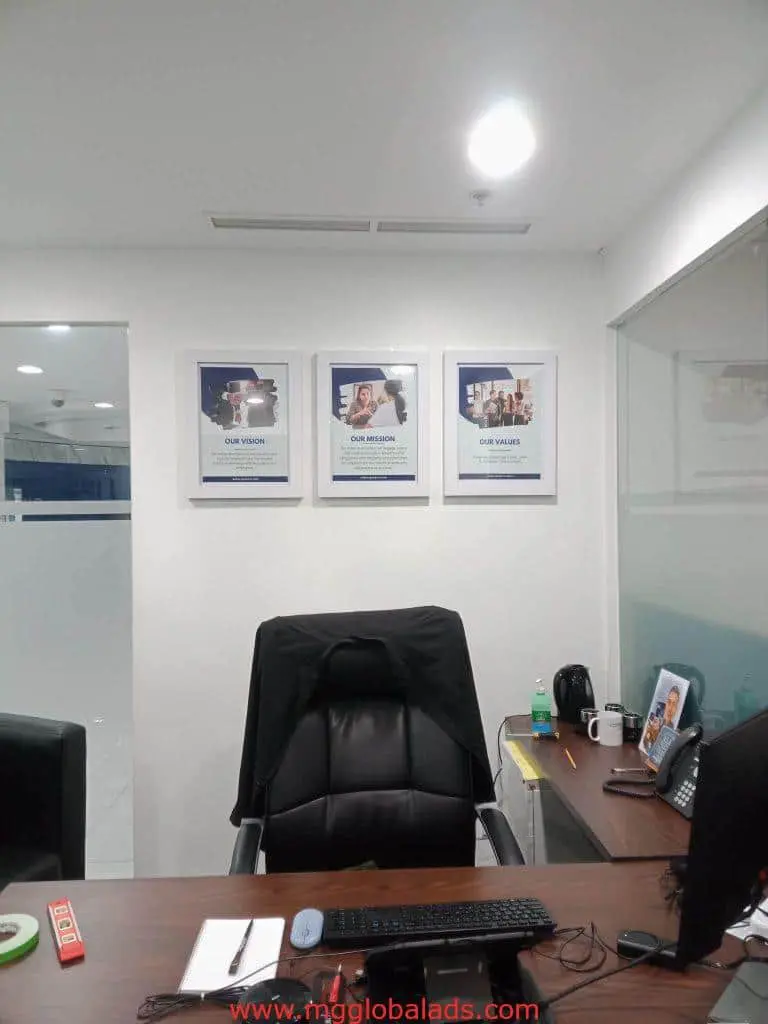 Office with desk, framed posters, and brushed metal mission-vision-values sign in Makati by M&G Global Ads.