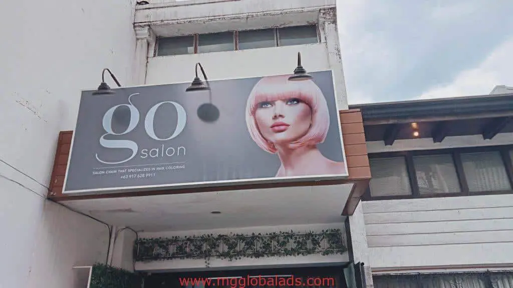 Metal sign for Go Salon in Makati shows a model with a pastel pink bob and hair color specialist info. By M&G Global Ads.