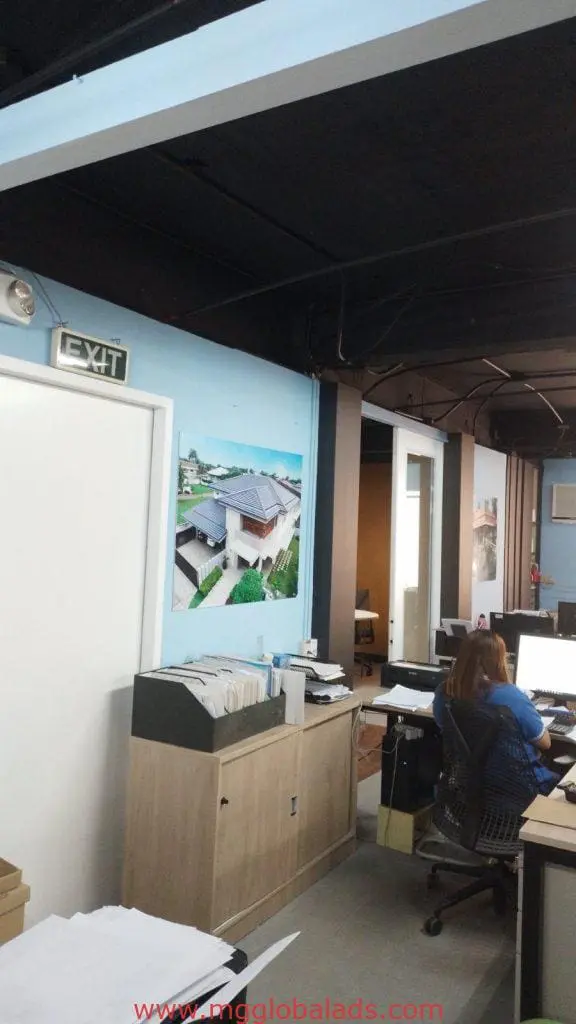 Office with desks, computers, LED door signage in Makati; filing cabinet and beachside photos on blue wall by M&G Global Ads.