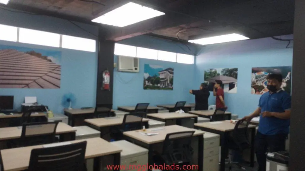 Office interior in Makati featuring custom indoor signage and large posters, three people talking; by M&G Global Ads.