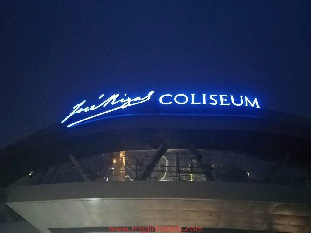 Blue LED building signage José Rizal COLISEUM on curved roof at night in Quezon City, glass facade lit up by M&G Global Ads.
