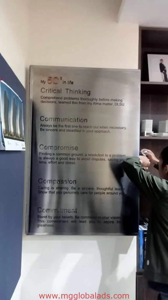 Indoor stainless engrave wall plaque signage listing company values in Makati, bookshelves beside the sign, by M&G Global Ads.