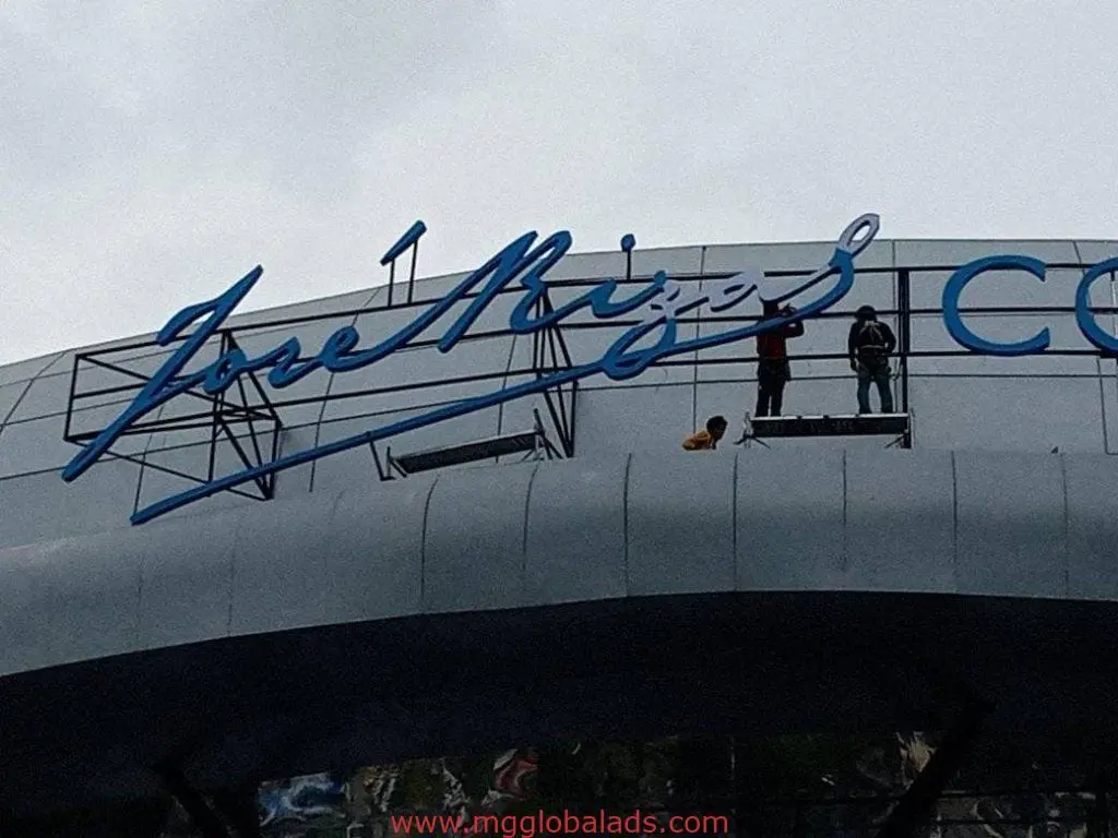 Acrylic building signage installation in elegant blue cursive on a modern exterior in Makati, by M&G Global Ads.