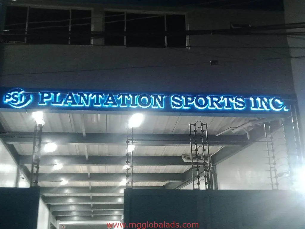 Bright blue acrylic signage for PLANTATION SPORTS INC. above entrance at night in Ortigas, by M&G Global Ads.