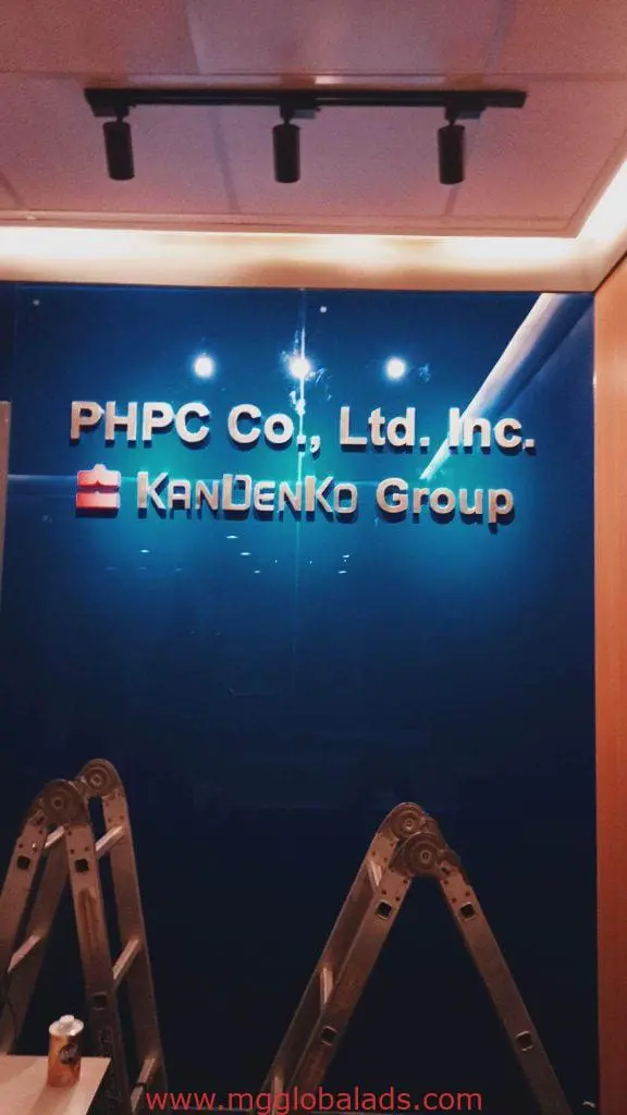 Silver acrylic office signage for PHPC Co., Ltd. Inc. and Kandenko Group in Makati, blue glass wall, by M&G Global Ads.