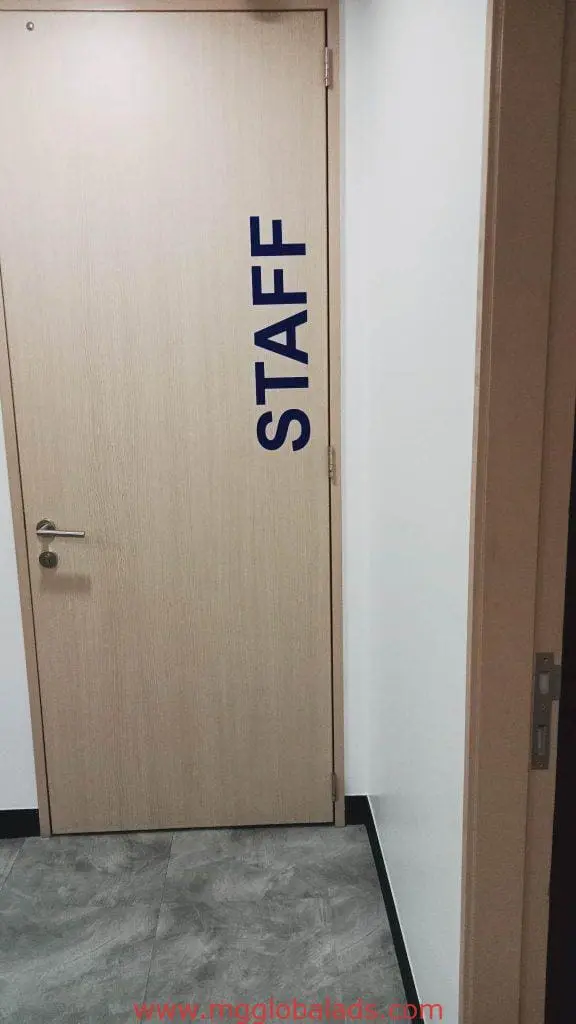 Staff room door building signage with blue letters on light wood in Makati hallway, clear design by M&G Global Ads.