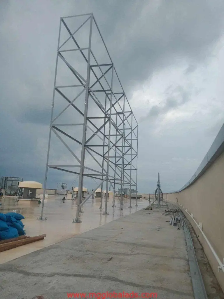 Building signage frame installation on a Makati rooftop, featuring equipment and blue sandbags, by M&G Global Ads.
